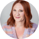 Headshot of a woman with red hair wearing a pastel knit top, smiling slightly at the camera.